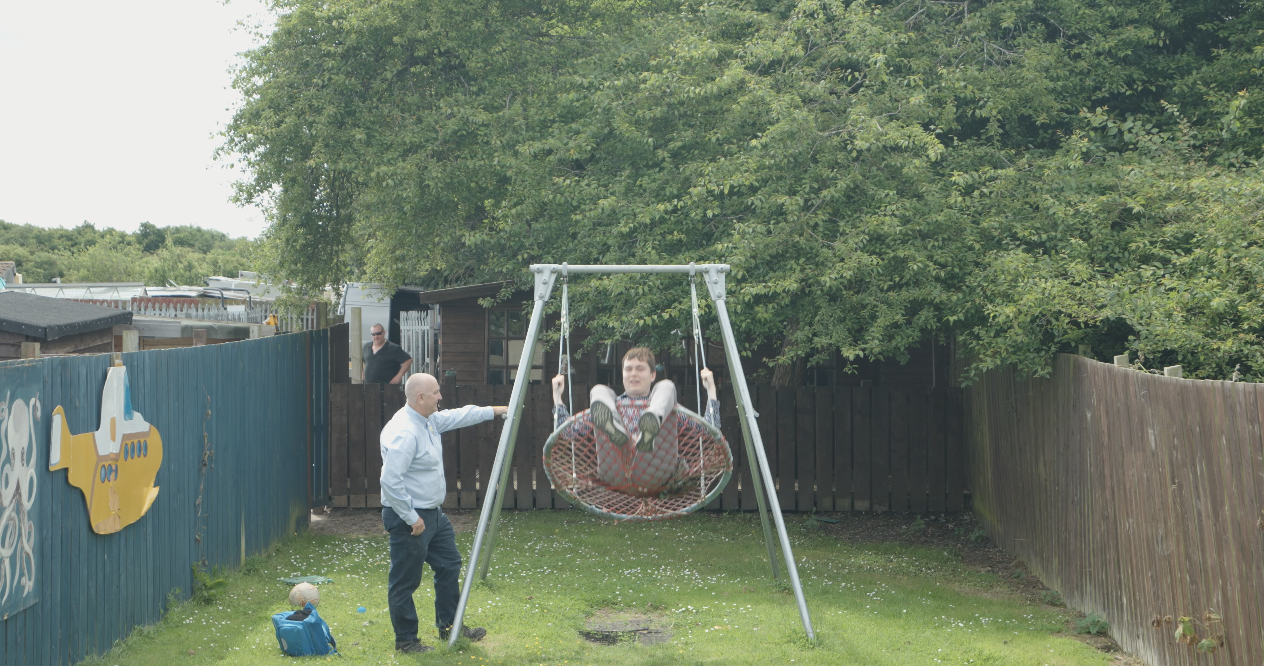 A photo of a managing director supporting a young person on a swing.