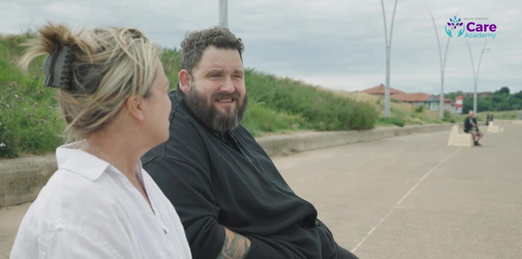 A photo of a social work practitioner with a person he is supporting.